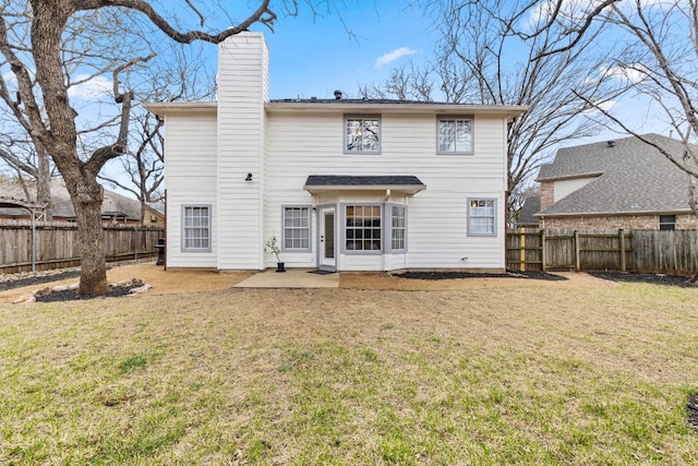 rear view of house featuring a patio area, a yard, a fenced backyard, and a chimney