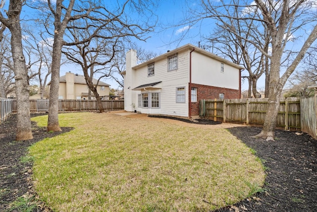 rear view of property with brick siding, a fenced backyard, a lawn, and a chimney