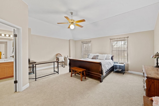 bedroom featuring baseboards, a sink, vaulted ceiling, ensuite bathroom, and light colored carpet