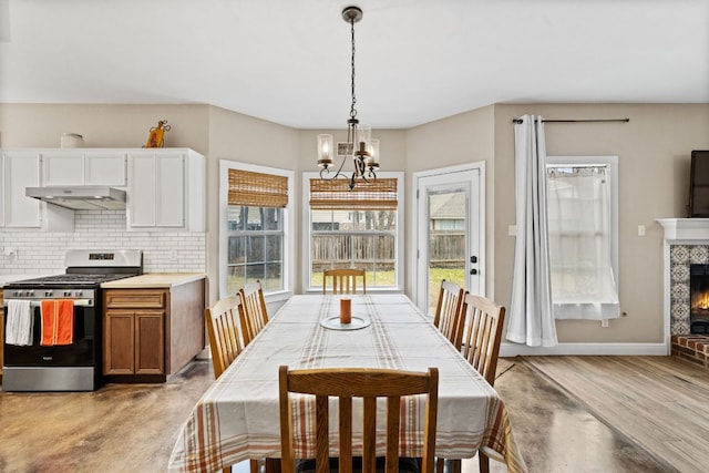 dining room with an inviting chandelier, light wood-type flooring, baseboards, and a lit fireplace