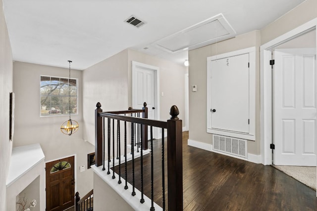 corridor with visible vents, an upstairs landing, dark wood-type flooring, and attic access