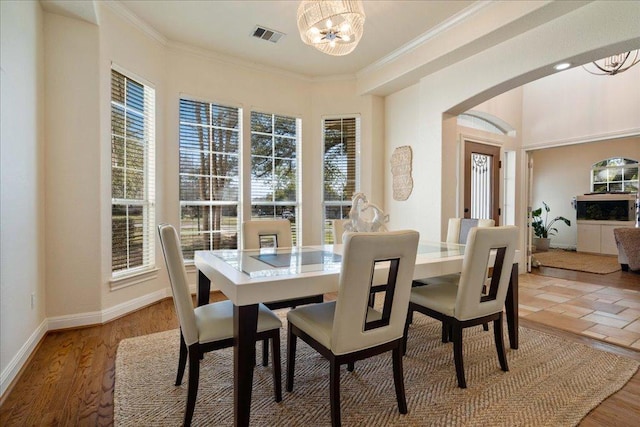 dining space with arched walkways, a notable chandelier, baseboards, and ornamental molding