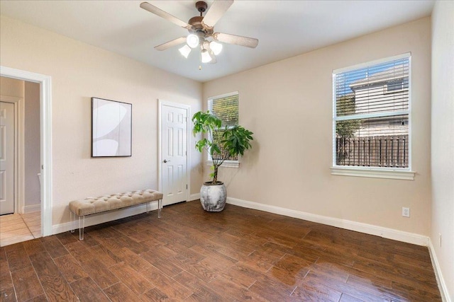 interior space with baseboards, a ceiling fan, and wood finished floors