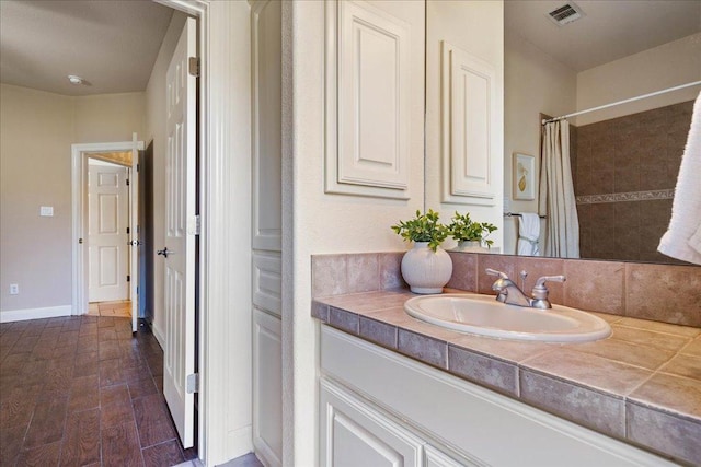 full bath featuring visible vents, a shower with curtain, wood finished floors, baseboards, and vanity