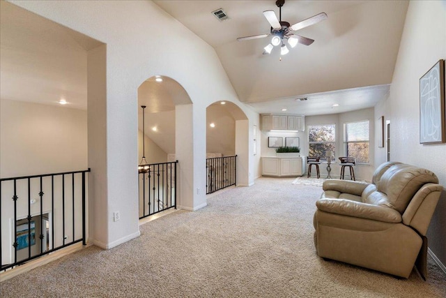 living area with baseboards, visible vents, high vaulted ceiling, ceiling fan, and light carpet