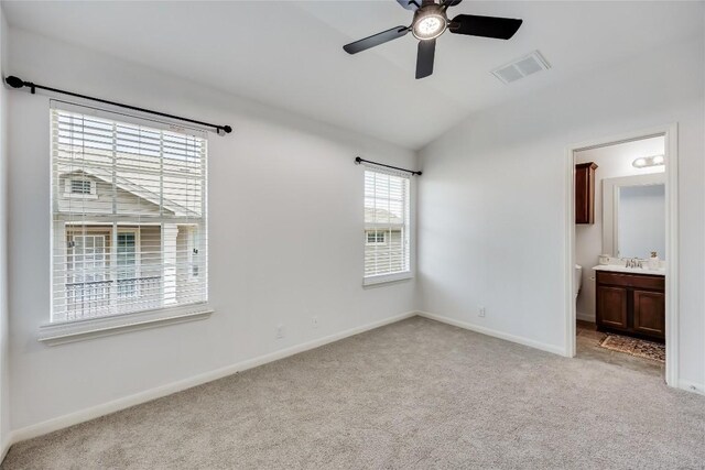 unfurnished bedroom with visible vents, baseboards, lofted ceiling, light carpet, and a sink