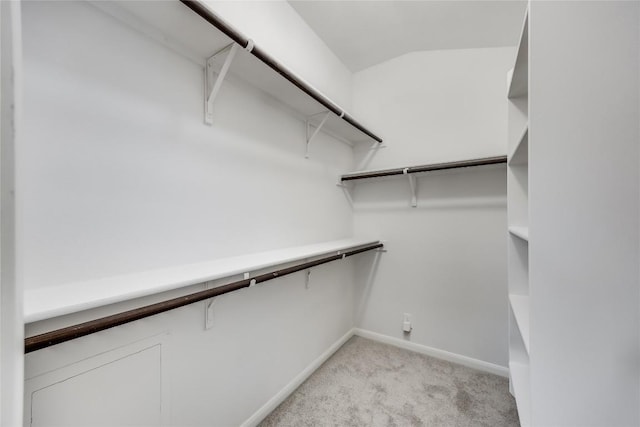 walk in closet featuring light carpet and lofted ceiling