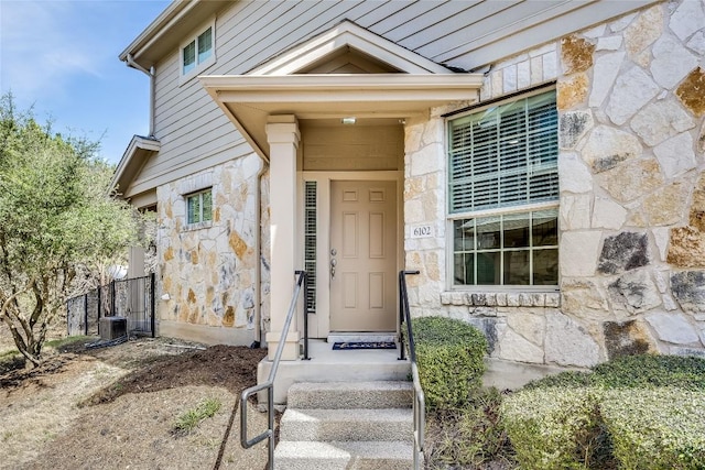 view of exterior entry featuring cooling unit and stone siding