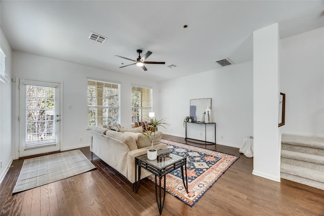 living area featuring visible vents, wood finished floors, ceiling fan, and stairs