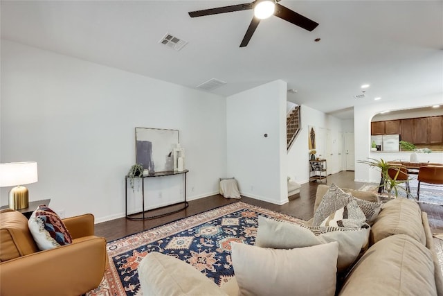 living area with visible vents, wood finished floors, arched walkways, baseboards, and ceiling fan