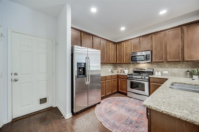 kitchen with tasteful backsplash, recessed lighting, appliances with stainless steel finishes, dark wood-style floors, and a sink