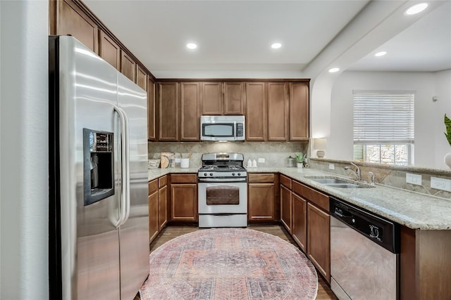 kitchen featuring a peninsula, arched walkways, a sink, stainless steel appliances, and backsplash