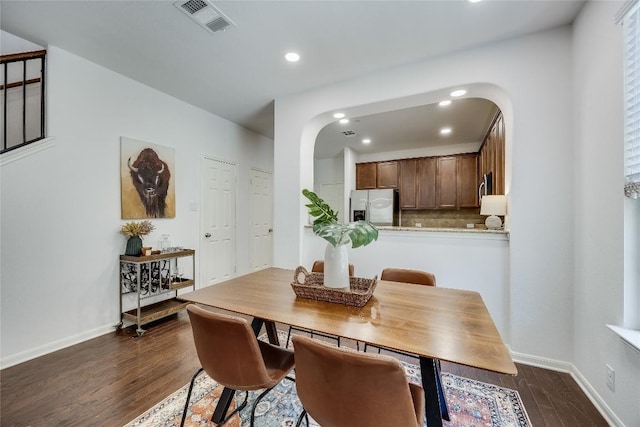 dining room featuring visible vents, baseboards, recessed lighting, arched walkways, and dark wood-type flooring