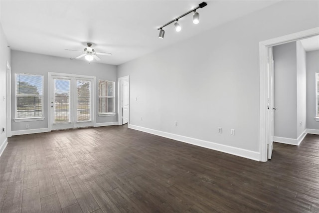 unfurnished living room with track lighting, baseboards, dark wood-type flooring, and a ceiling fan