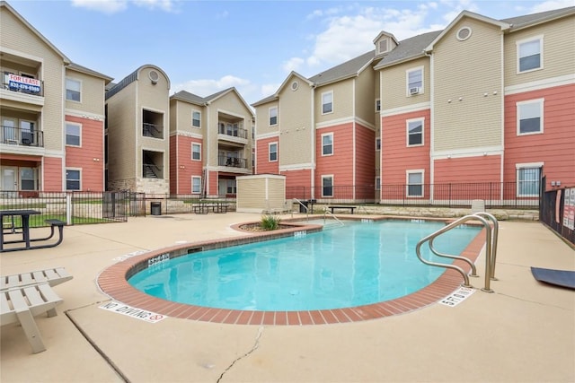 pool with a patio, fence, and a residential view