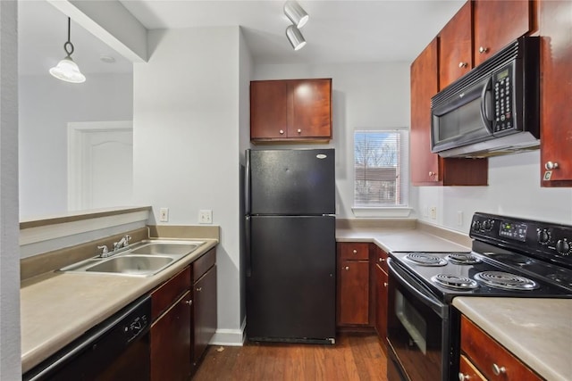 kitchen with dark wood-style flooring, a sink, black appliances, light countertops, and decorative light fixtures