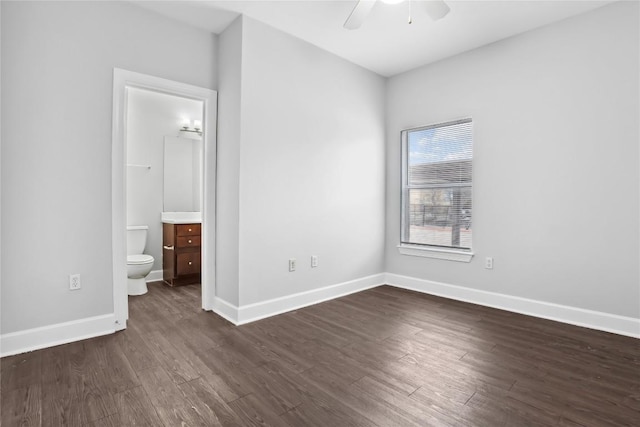 unfurnished bedroom with connected bathroom, baseboards, ceiling fan, and dark wood-style flooring