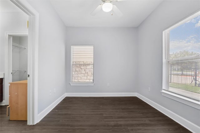 unfurnished room with baseboards, dark wood-type flooring, and ceiling fan