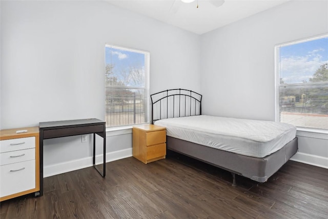 bedroom with dark wood-style floors, a ceiling fan, and baseboards