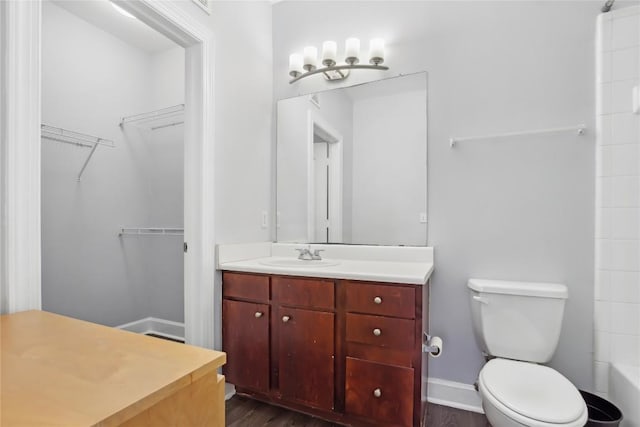 bathroom featuring baseboards, walk in shower, toilet, wood finished floors, and vanity