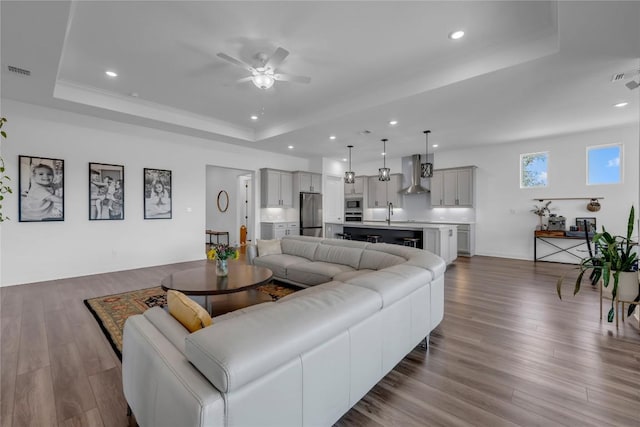 living room featuring visible vents, recessed lighting, a raised ceiling, a ceiling fan, and dark wood-style flooring