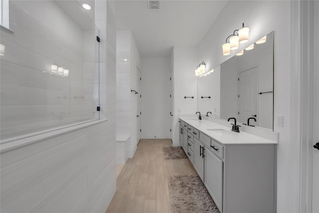 full bath featuring a sink, visible vents, wood finished floors, and double vanity