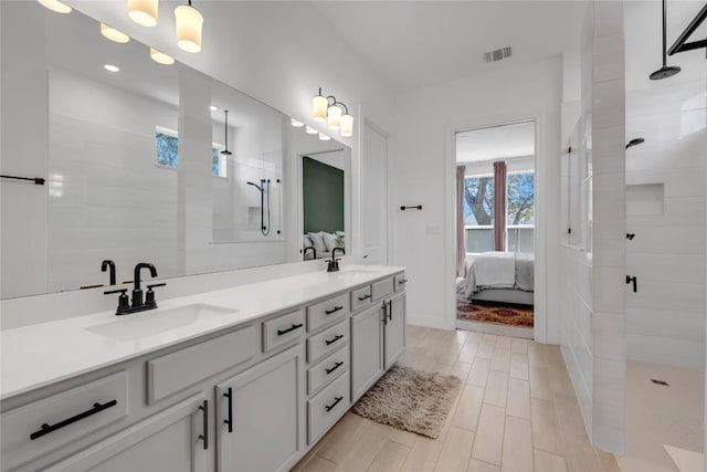 ensuite bathroom featuring walk in shower, visible vents, connected bathroom, and a sink