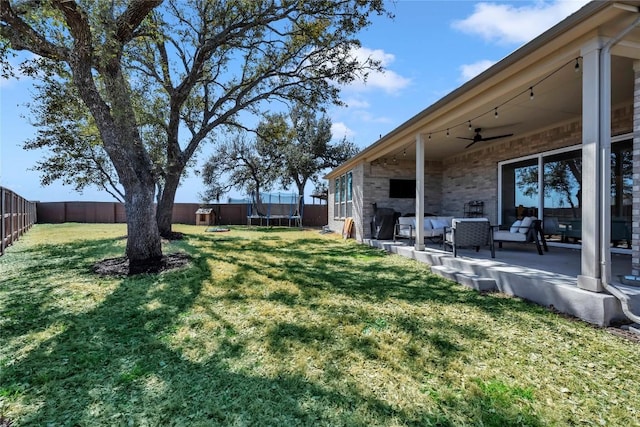 view of yard featuring ceiling fan, a trampoline, a fenced backyard, and a patio area