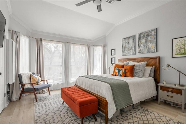 bedroom featuring ornamental molding, light wood-type flooring, ceiling fan, and vaulted ceiling