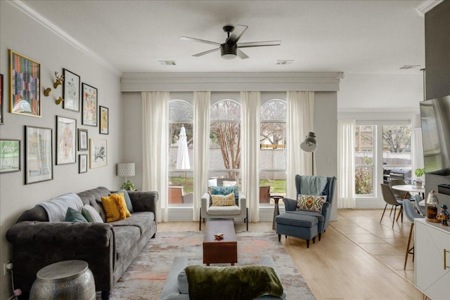 living area featuring visible vents, ornamental molding, and a ceiling fan