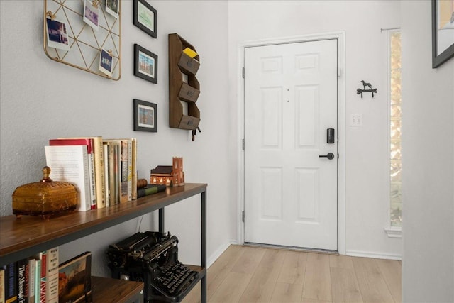 doorway featuring baseboards and light wood-style floors