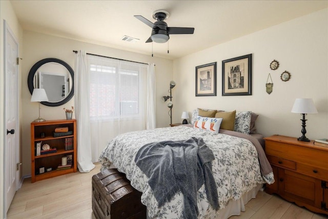 bedroom featuring light wood finished floors, visible vents, and a ceiling fan