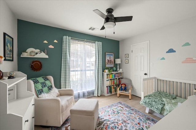 bedroom featuring light wood finished floors, visible vents, and ceiling fan