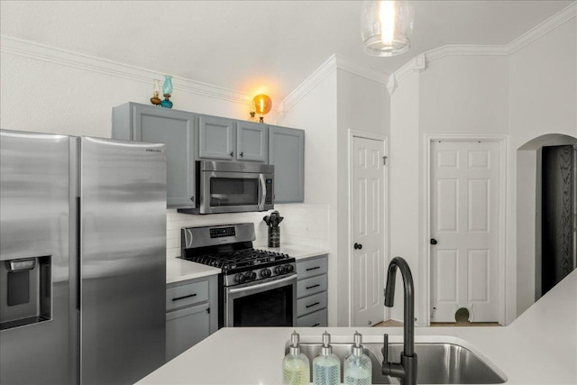 kitchen with light countertops, ornamental molding, decorative backsplash, gray cabinets, and appliances with stainless steel finishes