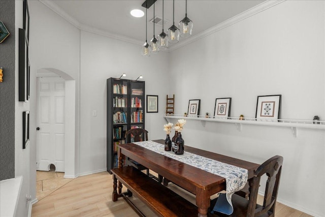 dining area with visible vents, arched walkways, light wood-style floors, crown molding, and baseboards