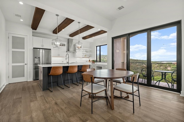 dining room featuring visible vents, beam ceiling, an inviting chandelier, and wood finished floors