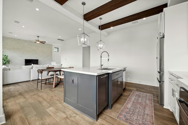 kitchen featuring a ceiling fan, visible vents, light wood finished floors, and a sink