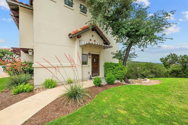 mediterranean / spanish-style home featuring stucco siding, a front yard, and a tile roof