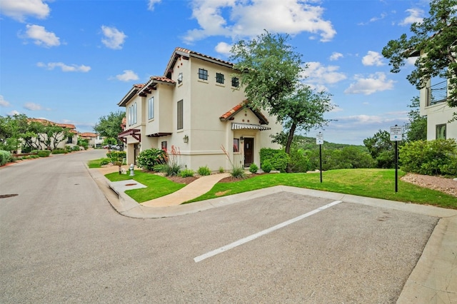 view of front of house featuring stucco siding, uncovered parking, a front lawn, and a tile roof