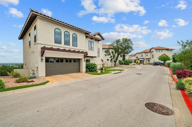 exterior space featuring stucco siding, driveway, a residential view, an attached garage, and a tiled roof