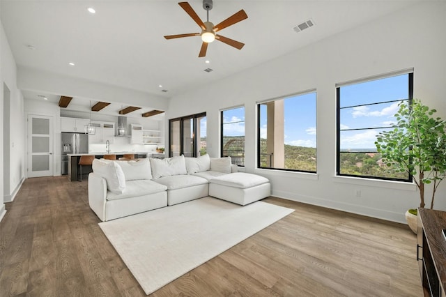 living area featuring visible vents, a healthy amount of sunlight, ceiling fan, and dark wood-style flooring