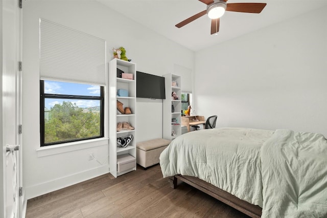 bedroom featuring a ceiling fan, baseboards, and wood finished floors