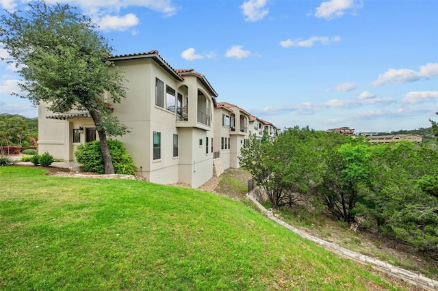 exterior space with a tiled roof, a lawn, and stucco siding