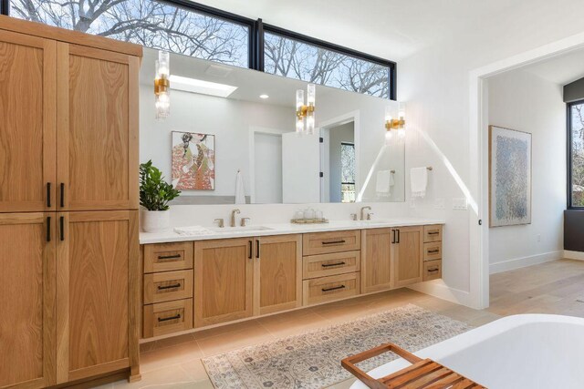 5514 Montview St, Austin, TX 78756 - full bath with double vanity, tile patterned flooring, a skylight, a bathtub, and baseboards