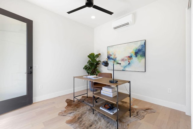 office featuring baseboards, a ceiling fan, a wall mounted AC, and light wood-style floors