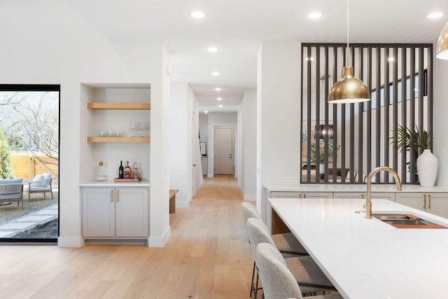 interior space featuring a sink, built in shelves, light wood-style flooring, and recessed lighting