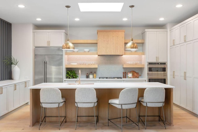 kitchen with open shelves, appliances with stainless steel finishes, a skylight, and a sink