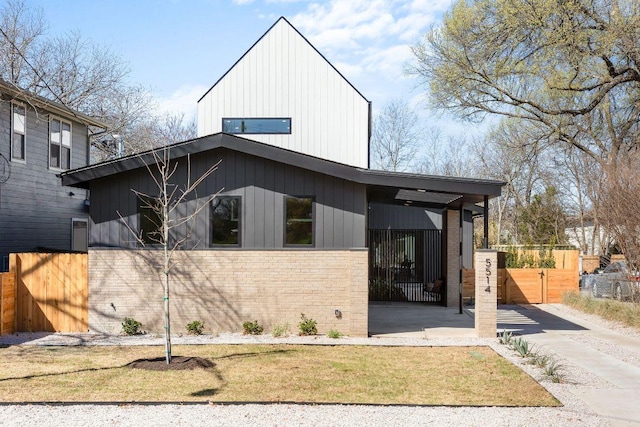 view of front of home featuring a gate, board and batten siding, brick siding, and fence