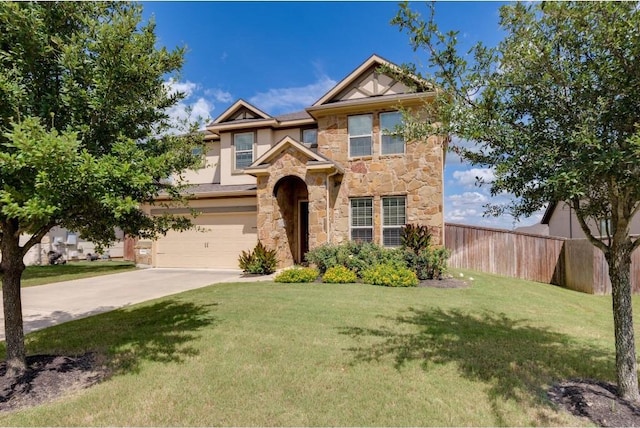 view of front of house featuring driveway, stone siding, fence, a front yard, and a garage