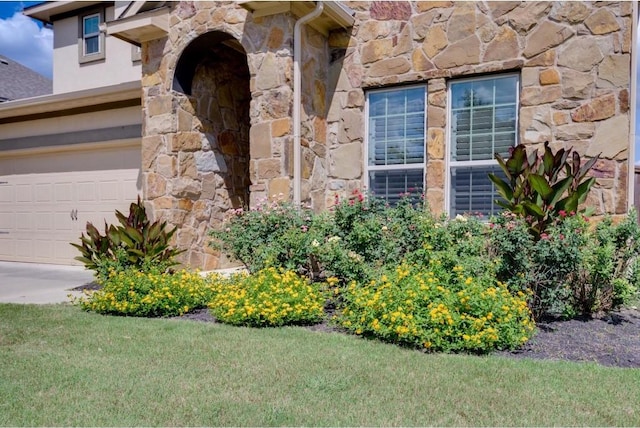 exterior details featuring stone siding and concrete driveway